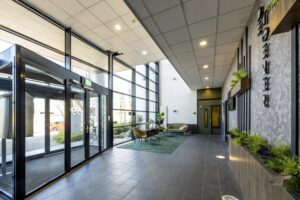 Modern entrance lobby of a building on Overschiestraat with large windows, seating area, and indoor plants.