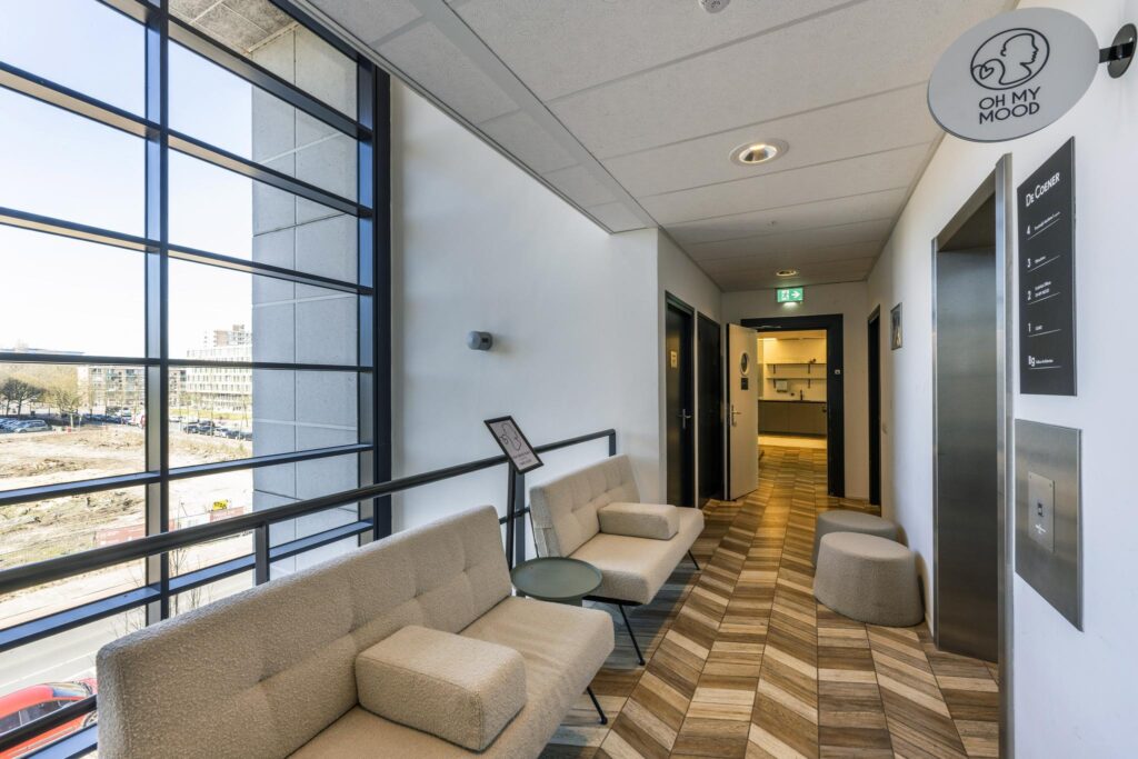 Modern waiting area with beige seating, large windows, and "Oh My Mood" signage in an office building on Overschiestraat.