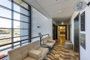 Modern waiting area with beige seating, large windows, and "Oh My Mood" signage in an office building on Overschiestraat.