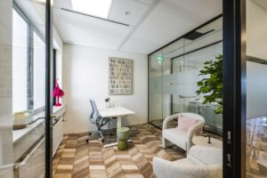 Modern office space on Overschiestraat with a desk, ergonomic chair, glass walls, and cozy seating area.