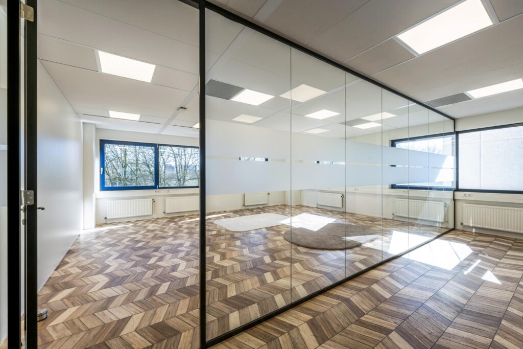 Modern office space on Overschiestraat with glass walls, patterned wooden flooring, and large windows.