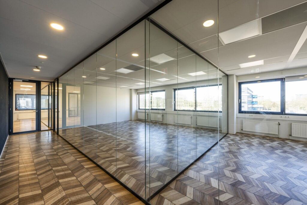 Modern office space on Overschiestraat with glass walls and geometric wooden flooring.
