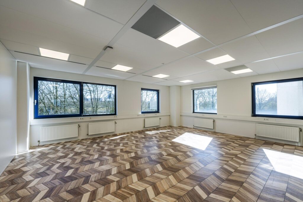 Bright, empty office space on Overschiestraat with large windows and a patterned wooden floor.