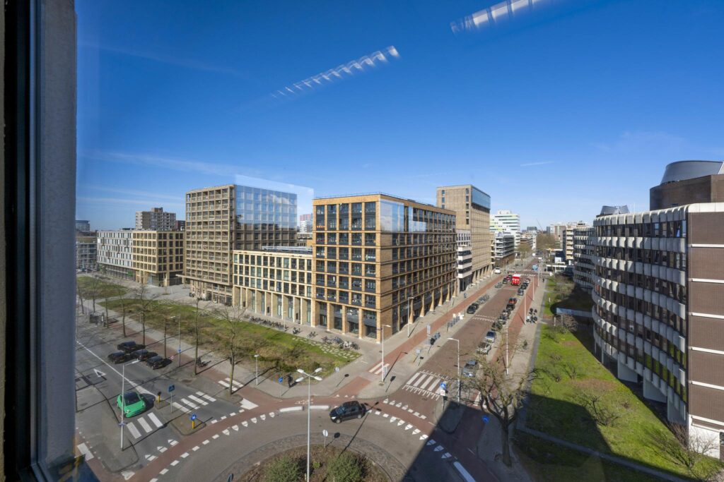 Street view of modern office buildings along Overschiestraat in Amsterdam on a clear, sunny day.