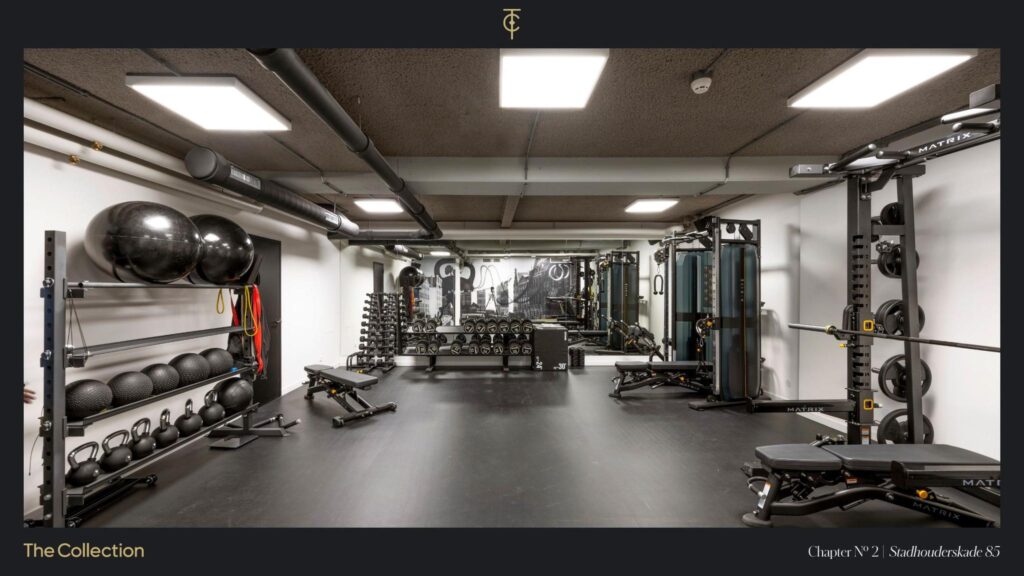 Modern gym room at Stadhouderskade 85 equipped with weights, benches, resistance bands, and various fitness machines.