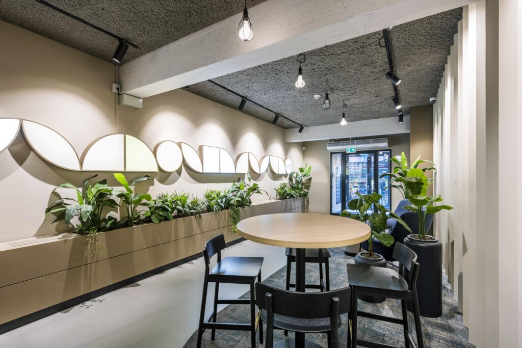 Moderne wachtruimte met ronde tafel, zwarte stoelen, veel groen en kunst aan de muur in Singel 174.