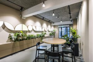 Moderne wachtruimte met ronde tafel, zwarte stoelen, veel groen en kunst aan de muur in Singel 174.
