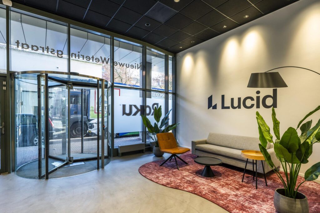 Modern office lobby of Lucid with a seating area, large plants, and a glass revolving door at Vijzelgracht.
