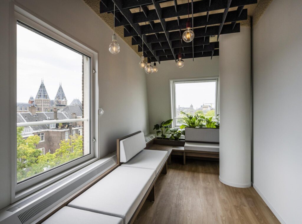 Modern seating area with large windows offering a view of the Rijksmuseum and surrounding Amsterdam rooftops.