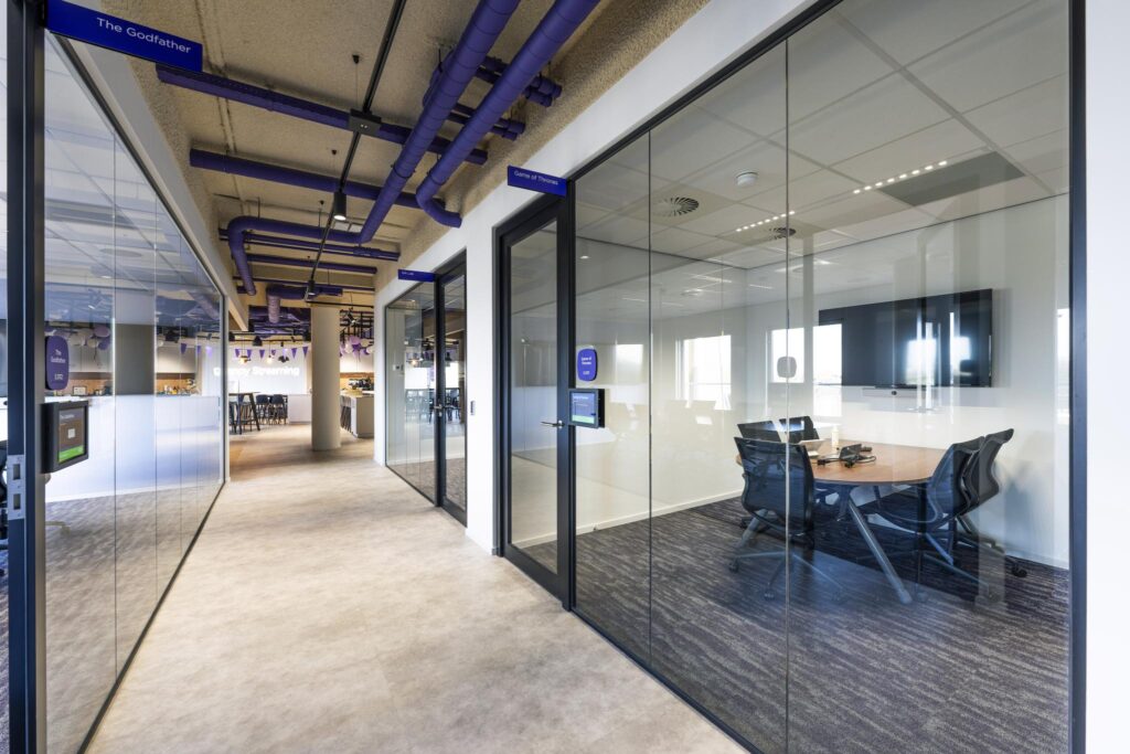 Modern office hallway with glass-walled meeting rooms named "The Godfather" and "Game of Thrones" at Vijzelgracht.