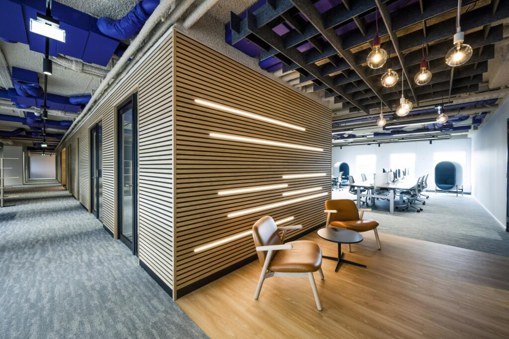Modern office interior at Vijzelgracht with a wooden slat wall, lounge chairs, and an open workspace.