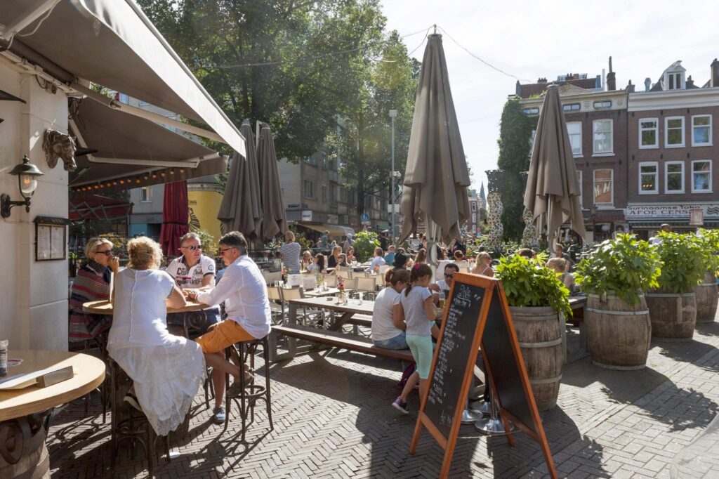 People enjoying a sunny afternoon on the outdoor terrace of a café at Vijzelgracht in Amsterdam.