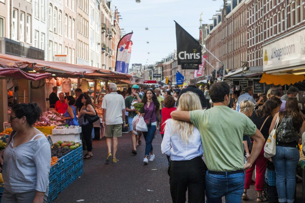 Busy street market on Vijzelgracht in Amsterdam with people shopping at various outdoor stalls.
