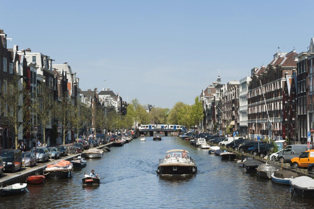 Boats on the Vijzelgracht canal in Amsterdam with a metro crossing the bridge in the background.