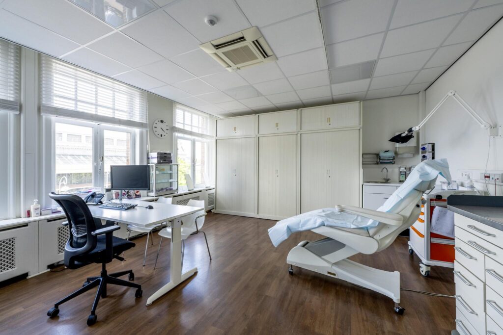 Modern medical consultation room with examination chair, desk, and computer at Concertgebouwplein.