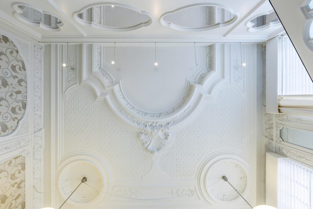 Ornate white ceiling with intricate plasterwork and decorative patterns in a historic building at Concertgebouwplein.