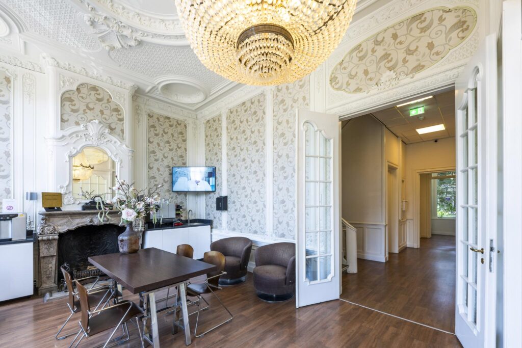 Elegant reception room at Concertgebouwplein with ornate ceiling, chandelier, and modern seating area.
