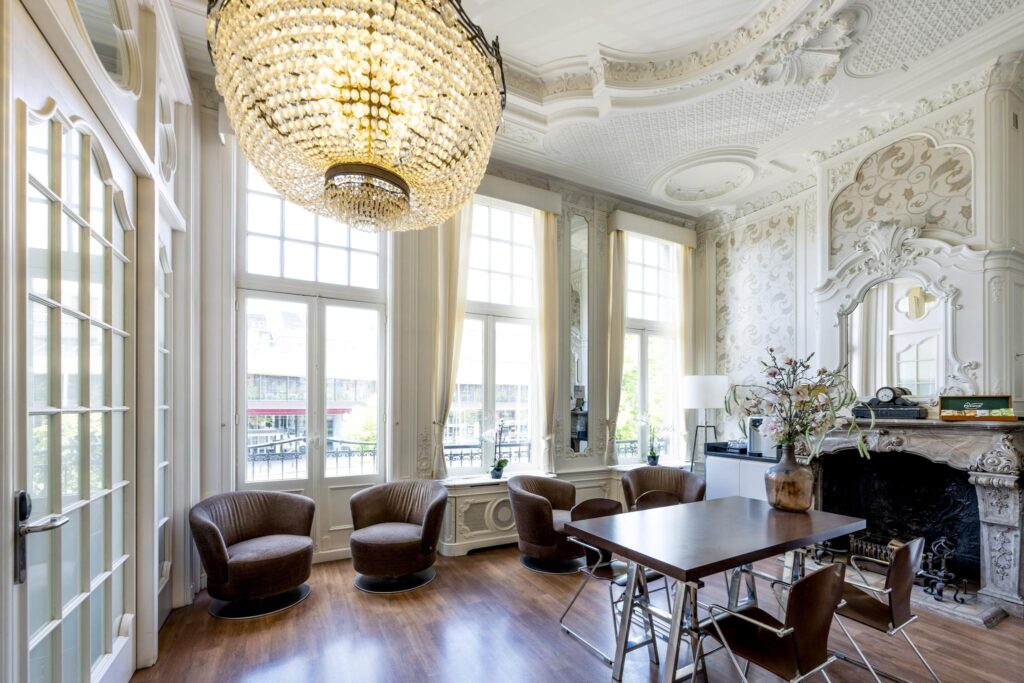 Elegant meeting room with ornate ceiling, large chandelier, and classic decor overlooking Concertgebouwplein.