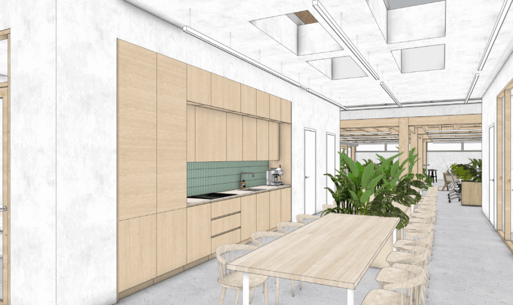 Modern office kitchen and dining area with light wood cabinetry, green tile backsplash, and communal seating along a long table.