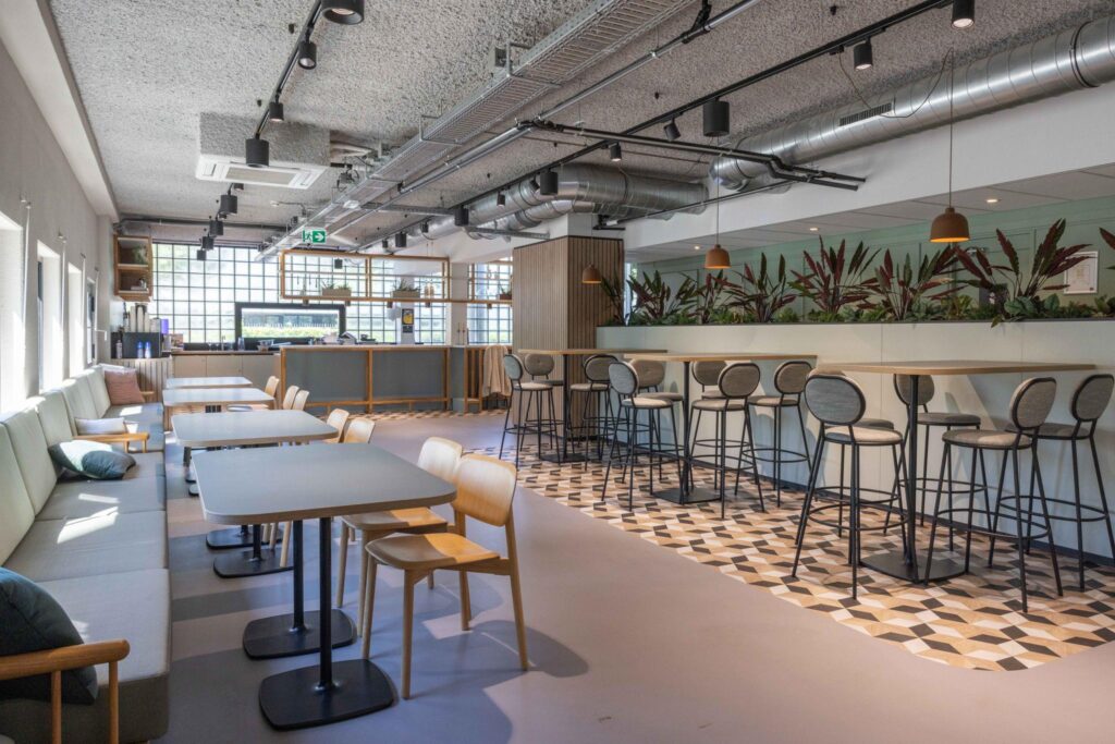 Modern communal workspace with a mix of lounge seating, bar stools, and natural light at Overschiestraat.