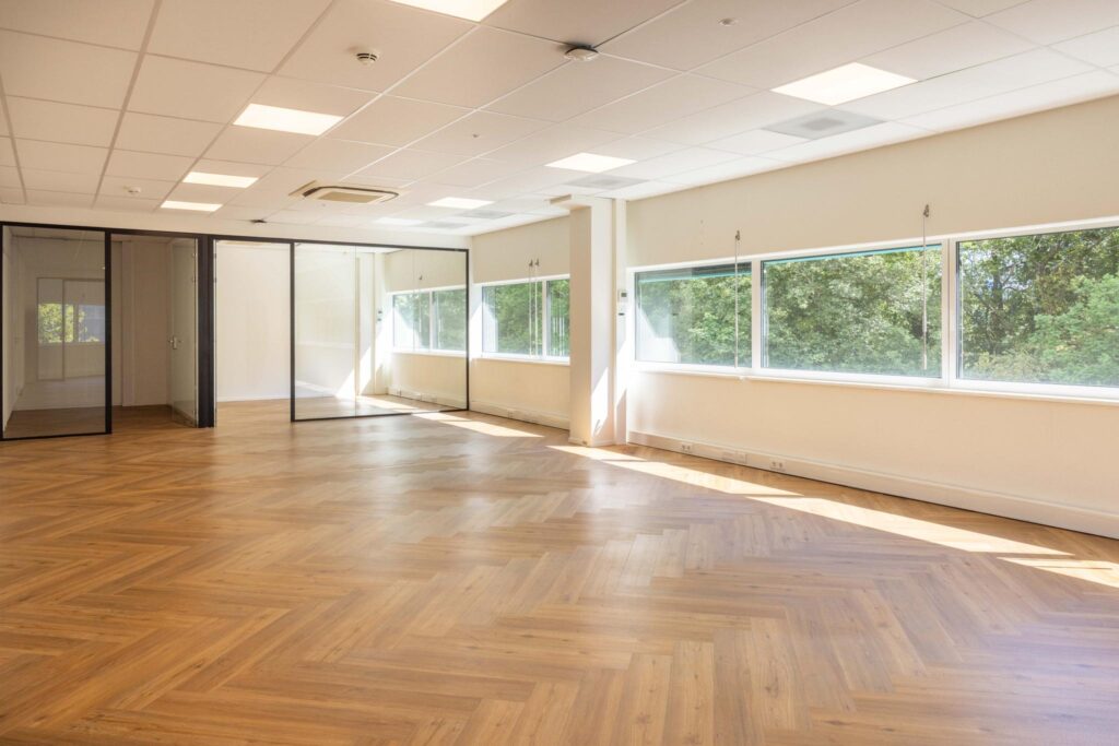 Bright and spacious office space on Overschiestraat with large windows, glass partitions, and herringbone wooden flooring.