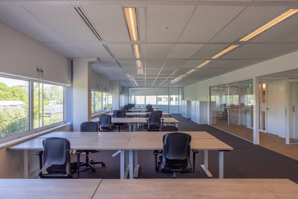 Modern open-plan office space on Overschiestraat with multiple desks, office chairs, and large windows providing natural light.