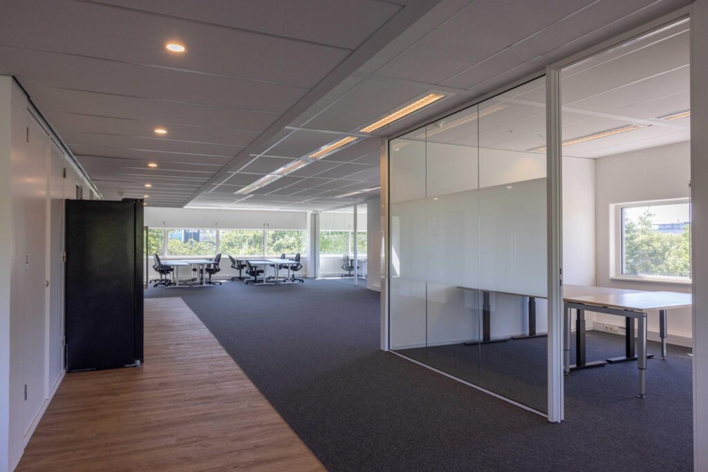 Modern open office space with glass-walled meeting room and large windows at Overschiestraat.
