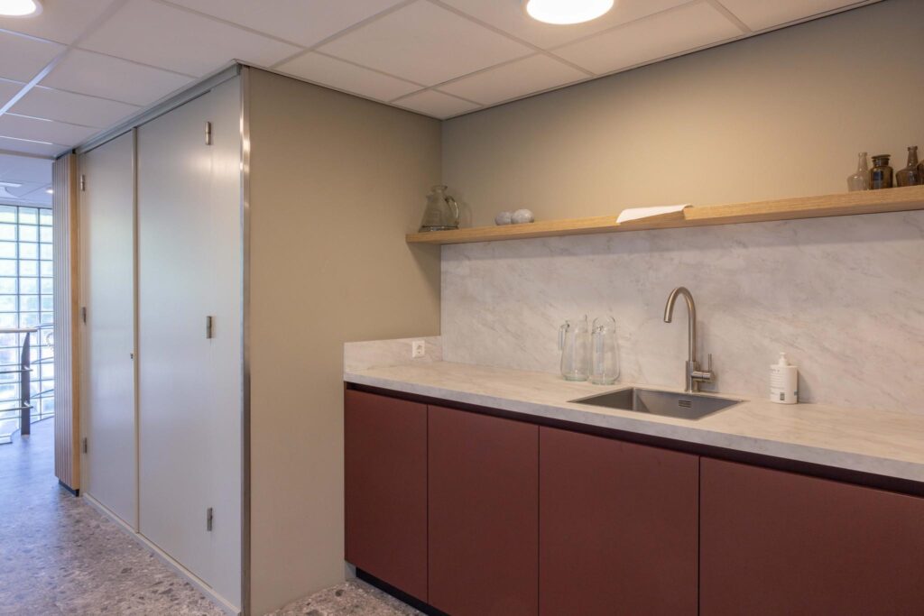 Modern kitchenette at Overschiestraat with a marble backsplash, built-in sink, and minimalist shelving.