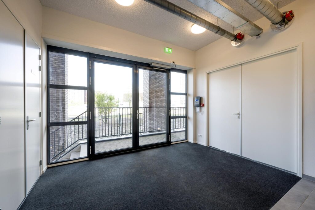 Entrance area with double glass doors leading to an outdoor ramp with metal railings.