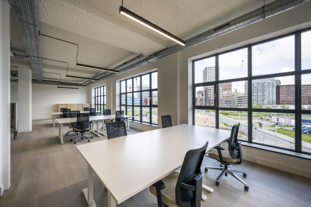 Modern open-plan office space with large windows overlooking a city construction site.