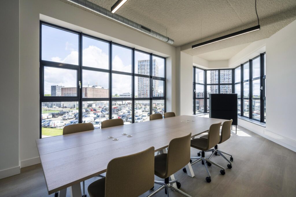 Modern meeting room with large windows offering a cityscape view and natural light.