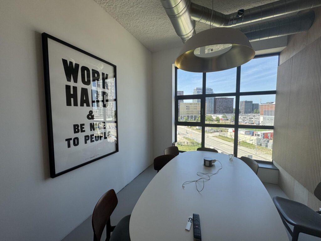 Modern meeting room with a motivational poster and a view of the Hellingbaan in a cityscape.