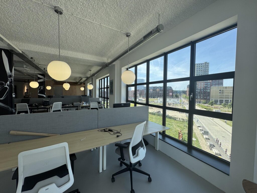 Modern office space with large windows overlooking the Hellingbaan area and nearby buildings.