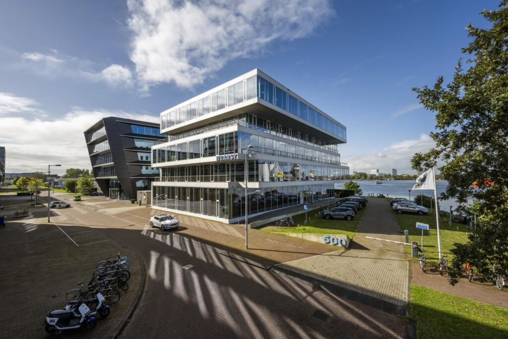 Modern office building at Moermanskade 500 in Amsterdam with waterfront parking and surrounding contemporary architecture.