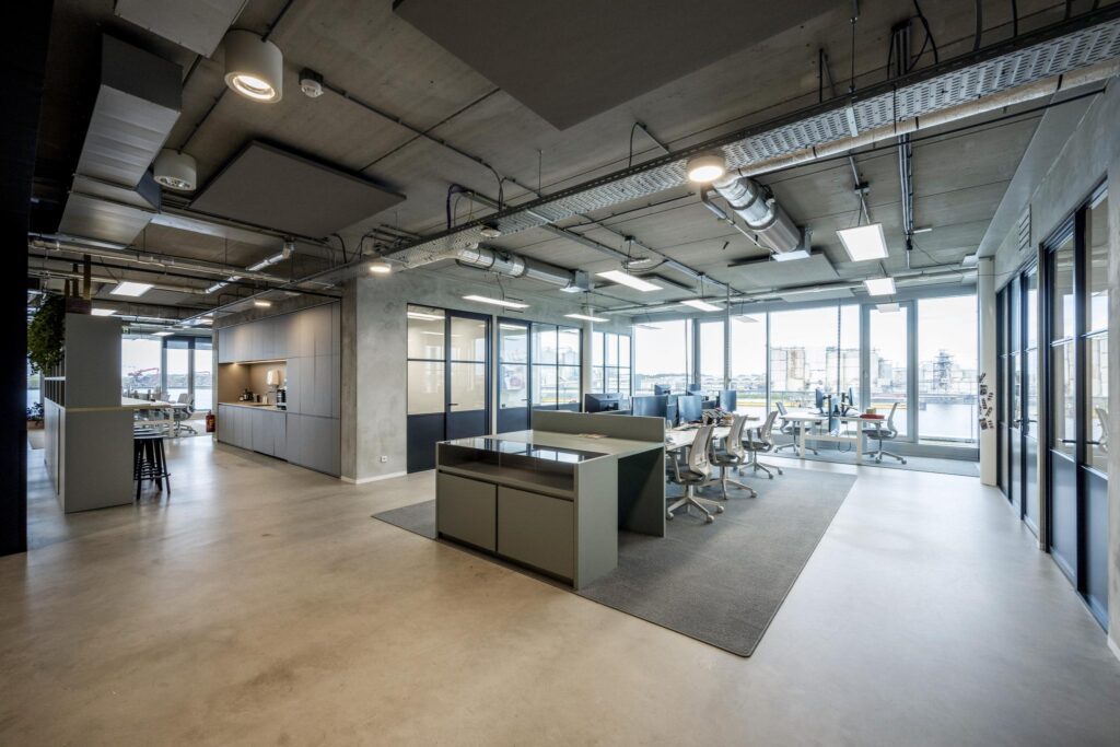 Modern open-plan office space on Moermanskade with industrial-style interior and large windows overlooking the water.