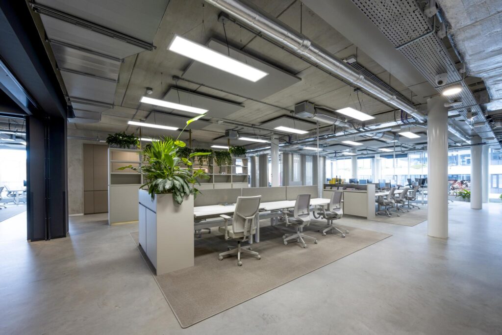 Modern open-plan office at Moermanskkade with shared workstations, ergonomic chairs, and green indoor plants.