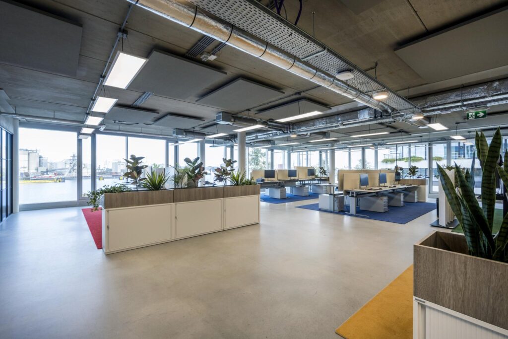 Modern open-plan office space on Moermanskade with workstations, large windows, and indoor plants.