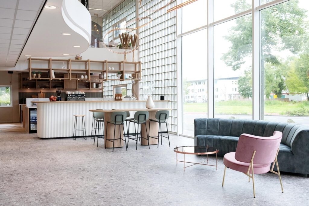 Modern lounge area with a stylish bar, high stools, and large windows at Overschiestraat.