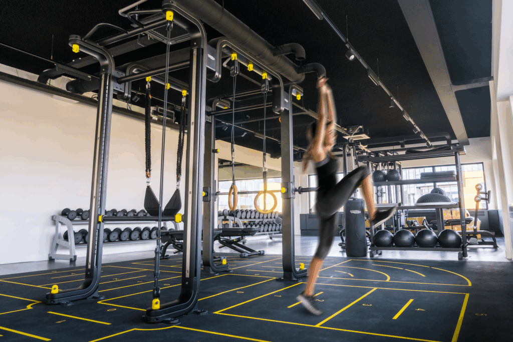 Modern gym with functional training equipment and a person in motion performing a dynamic exercise.