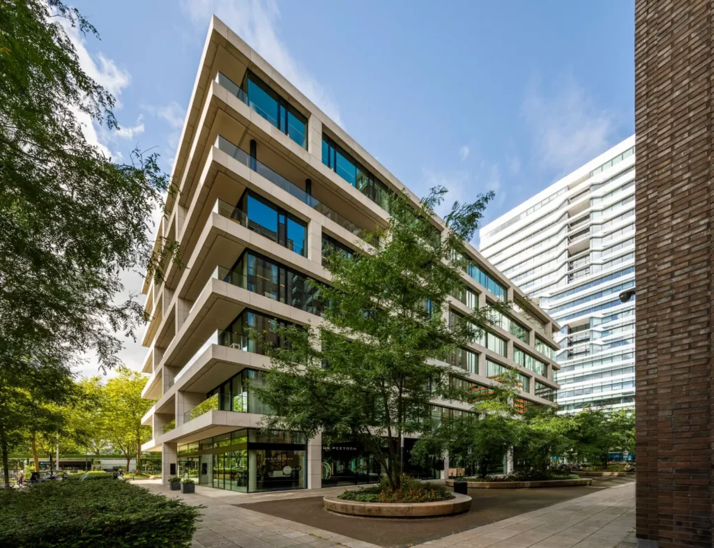 Modern office building on Gustav Mahlerlaan surrounded by trees and high-rise architecture in Amsterdam.