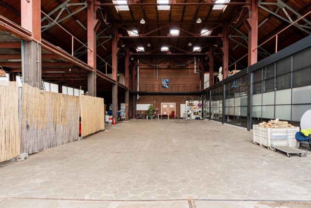 Spacious industrial warehouse interior on Sloterweg with high ceilings, exposed steel beams, and various workspaces.