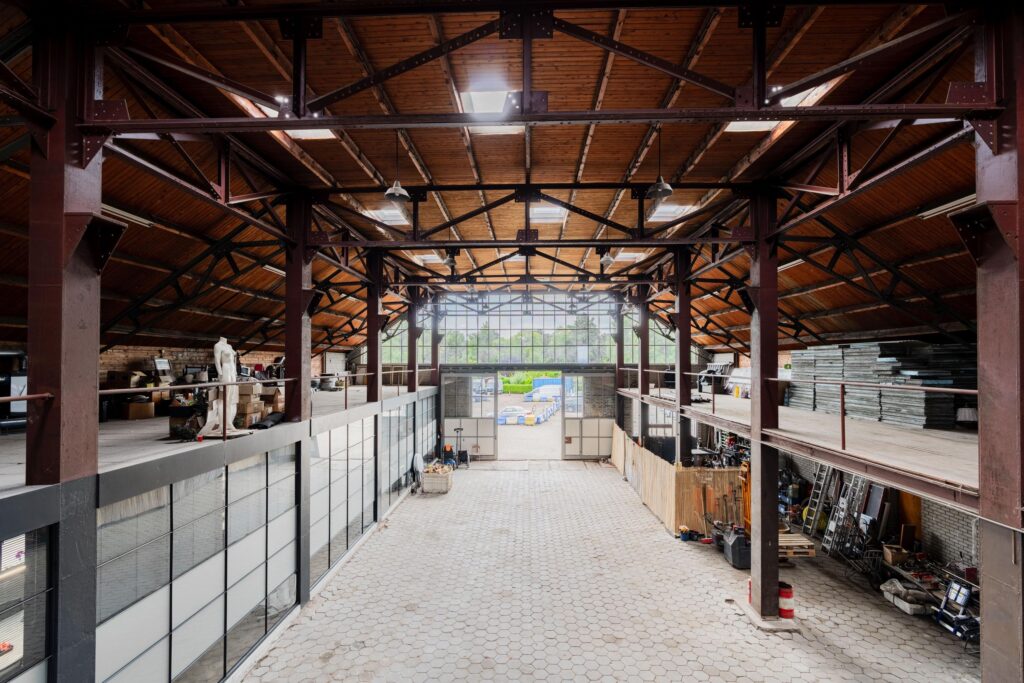 Interior view of a spacious industrial warehouse on Sloterweg with a high wooden ceiling, steel beams, and mezzanine storage areas.