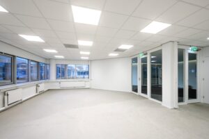 Leeg, wit kantoorruimte met grote ramen en systeemplafond aan de Kuiperbergweg.