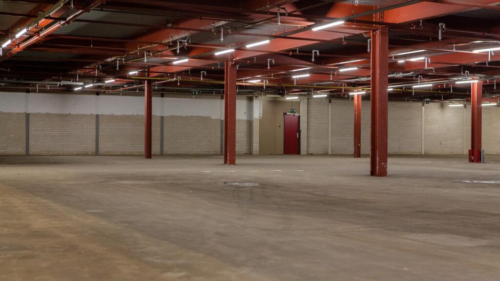 Empty industrial space with red steel beams and concrete floor at Weesperstraat.