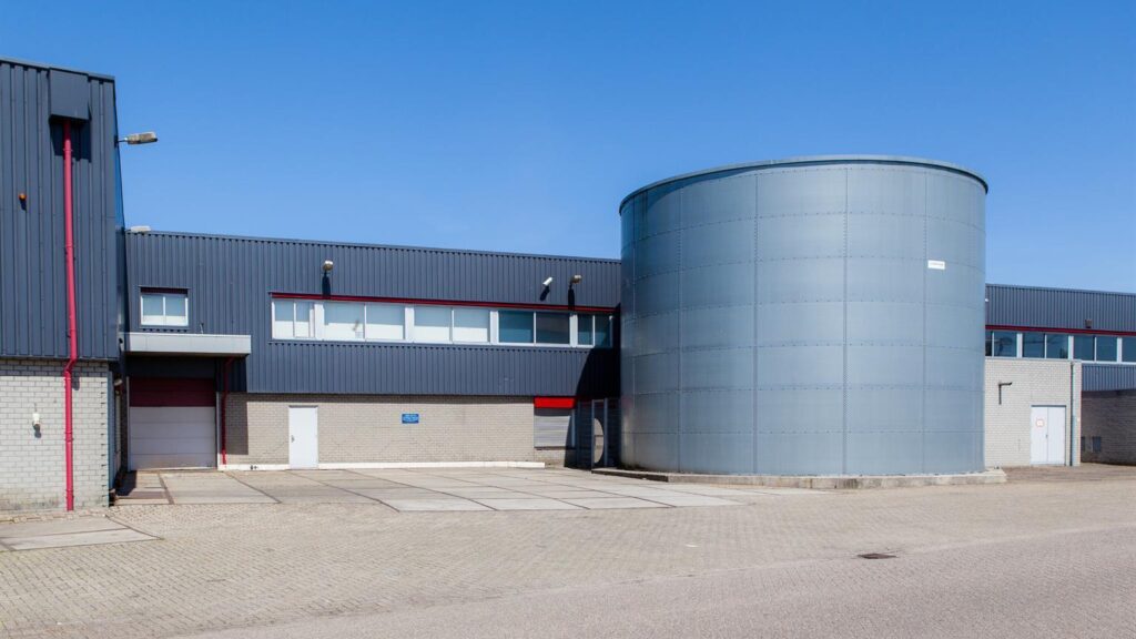 Industrial building on Weesperstraat with a large cylindrical metal silo in the foreground.