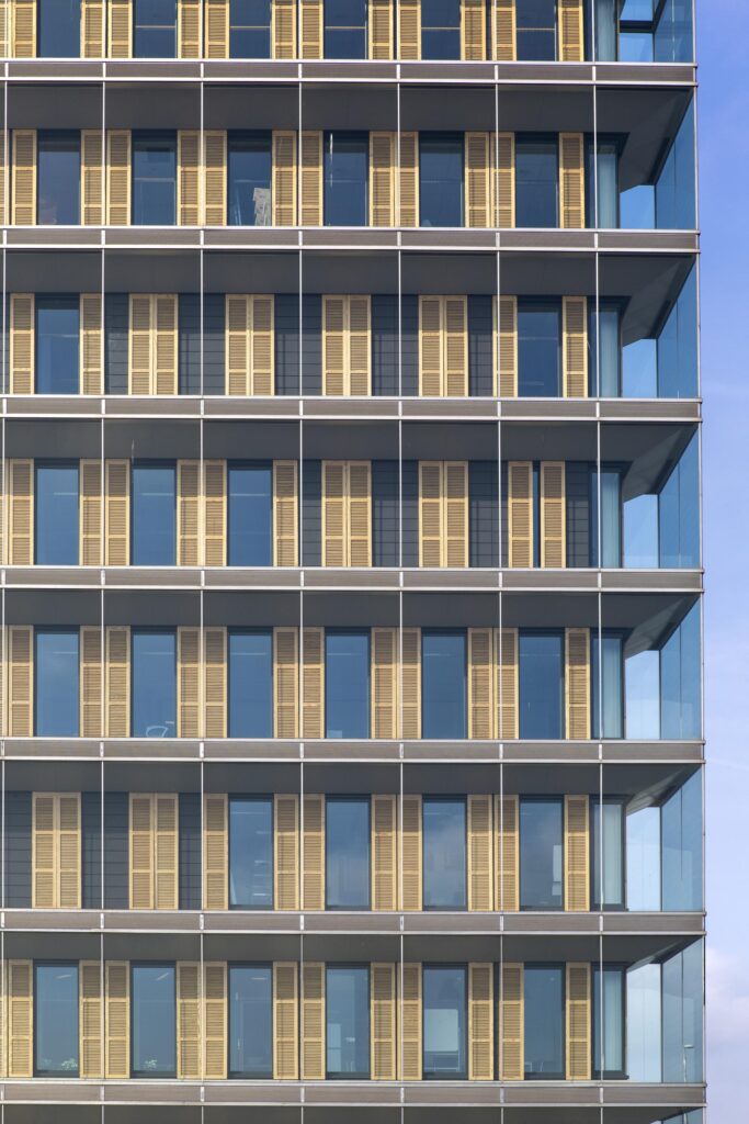 Modern office building on Paasheuvelweg with large glass windows and wooden shutters.