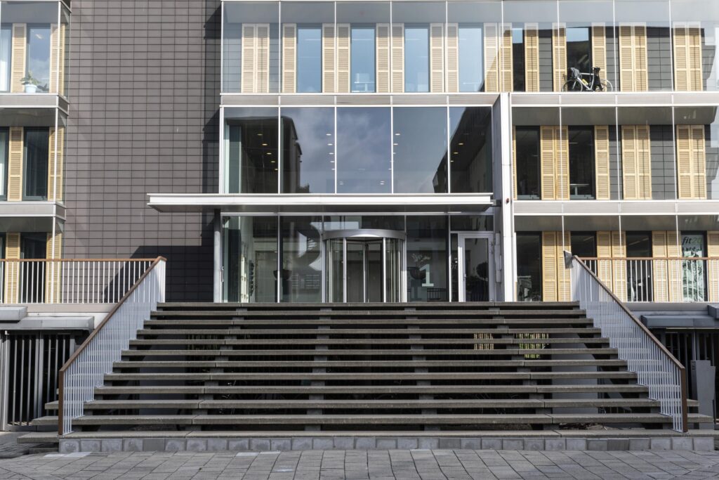 Front entrance of the office building at Paasheuvelweg 1 with wide stairs and glass facade.