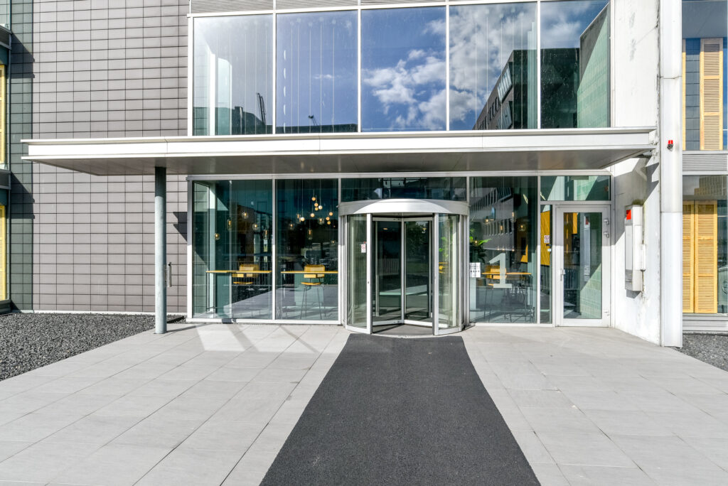 Main entrance of the office building at Paasheuvelweg 24 with a revolving glass door and modern facade.