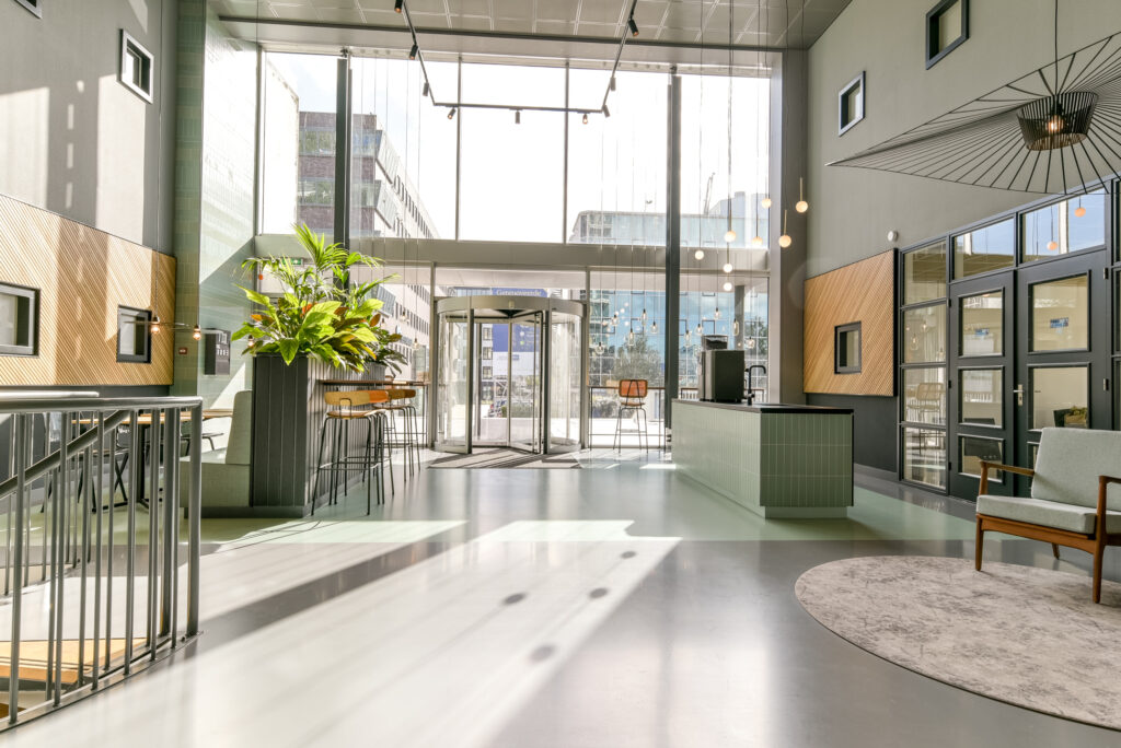 Modern and bright office lobby at Paasheuvelweg with high ceilings, large windows, and contemporary furnishings.