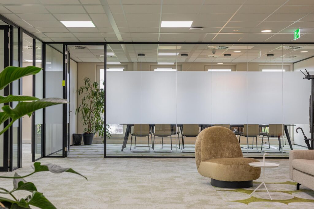 Modern office interior at Paasheuvelweg 175 with glass-walled meeting room, indoor plants, and contemporary lounge seating.
